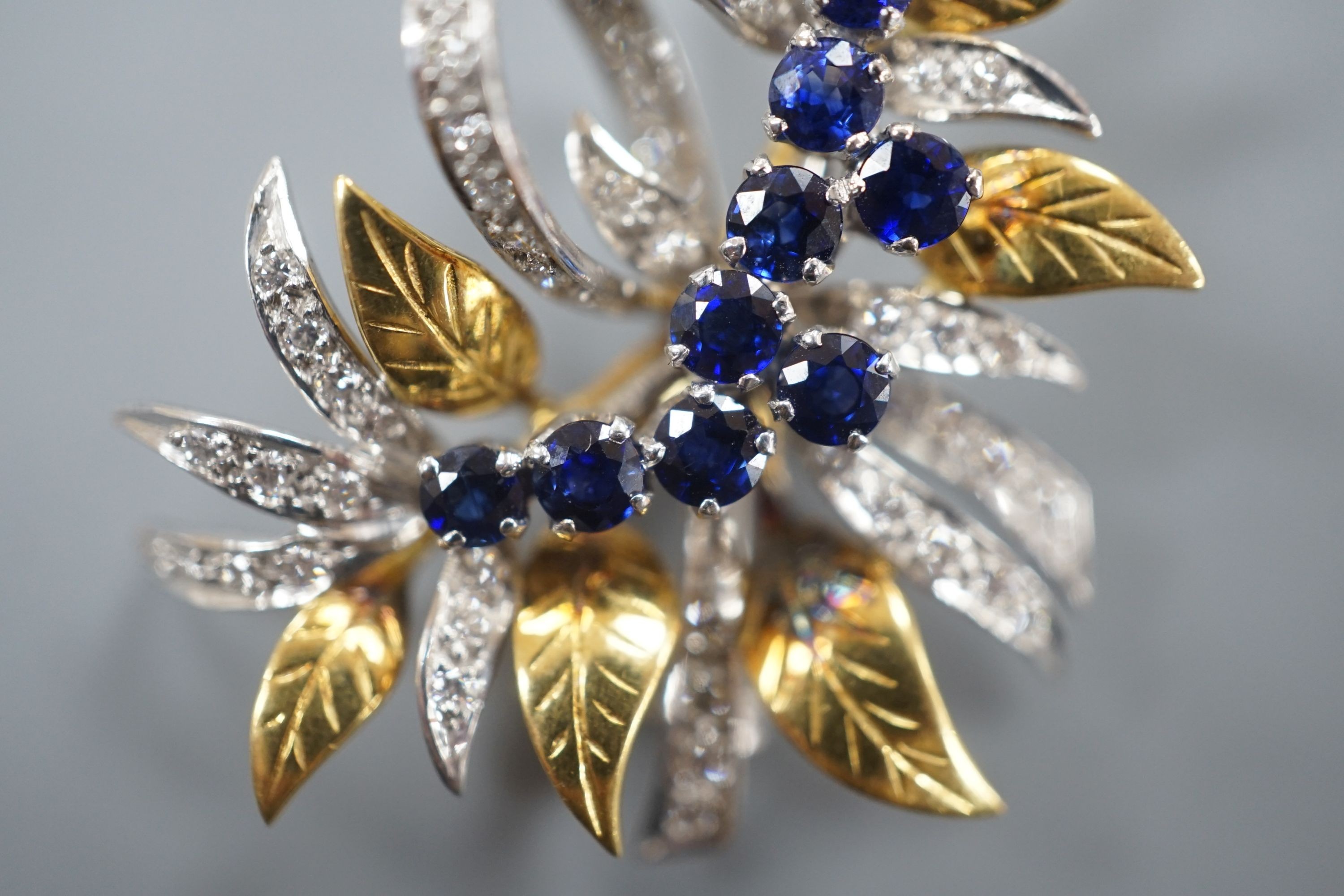 A modern 18ct two colour gold, sapphire and diamond set floral spray brooch, by Cropp & Farr, 38mm, gross weight 11.9 grams.